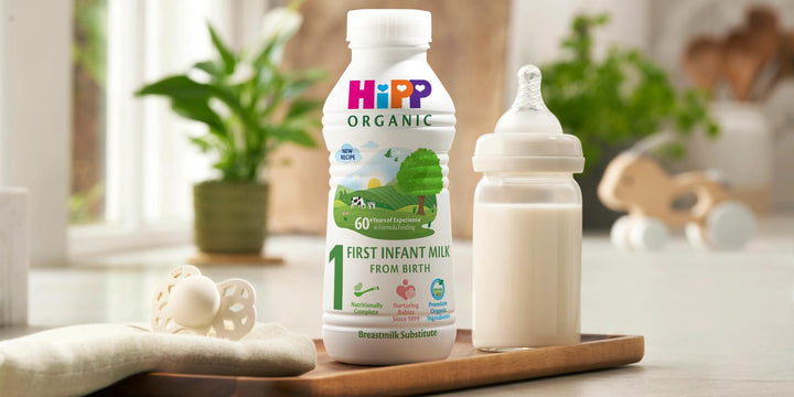 HiPP Organic baby milk bottle and container on a wooden tray with a blurred background